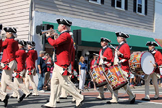 A group of men in red and white uniforms marching down a street. Description generated by AI