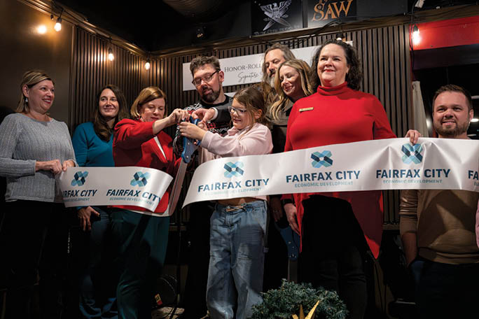 A group of people are cutting a ribbon with scissors. Description generated by AI