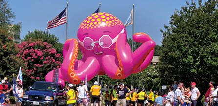 A large pink inflatable octopus with sunglasses on its head. Description generated by AI