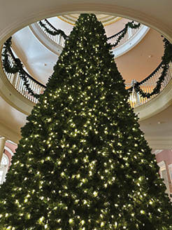A large, lit Christmas tree is in a room with a spiral staircase. AI generated content