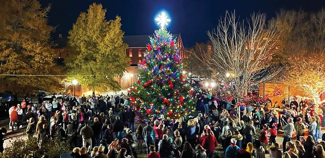 A large crowd of people gathered around a Christmas tree in a city square. AI generated content