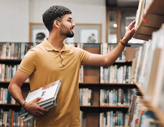 Student man, search bookshelf and library for reading, information and knowledge at university. College student, research and studying for education, college and learning for scholarship in Marseille