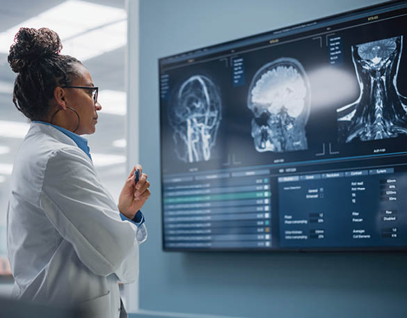 Medical Science Hospital: Confident Black Female Neurologist, Neuroscientist, Neurosurgeon, Looks at TV Screen with MRI Scan with Brain Images, Thinks about Sick Patient Treatment Method. Saving Lives