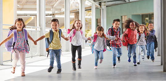 Primary school kids run holding hands in corridor, close up