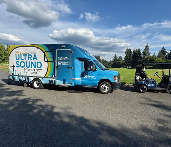 A blue truck with a white logo on the side is parked next to a golf cart. Description generated by AI