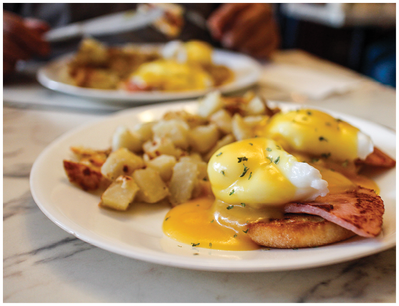 A plate of food with eggs, potatoes, and ham. Description generated by AI