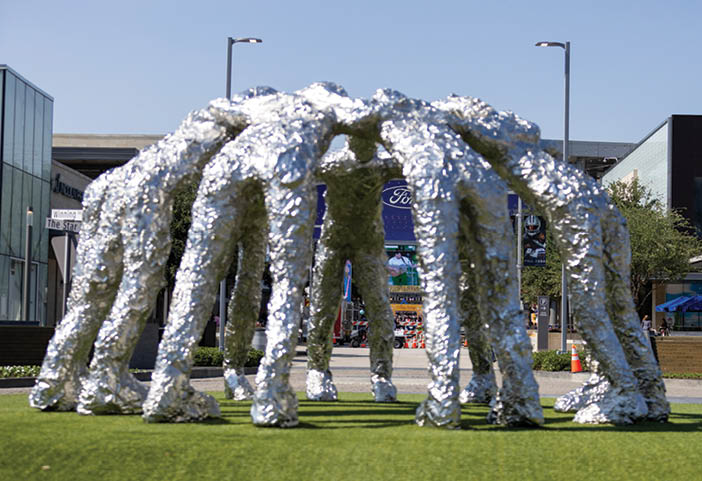A large metal sculpture of people standing together is on display in a park. AI generated content