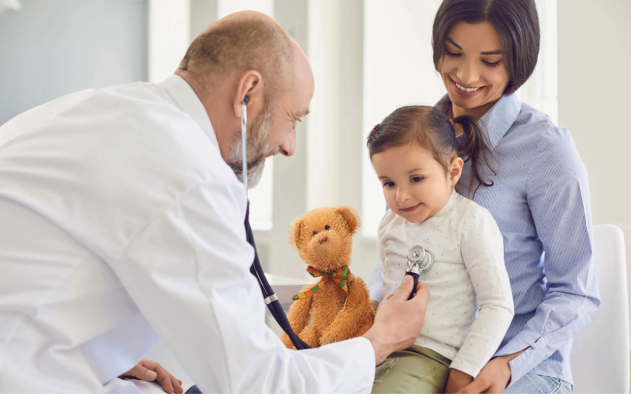 A man wearing a white coat is examining a young child. The child is holding a teddy bear. AI generated content