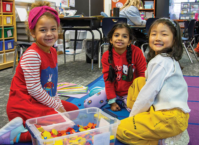 Three children are sitting on the floor, smiling and playing with toys. AI generated content