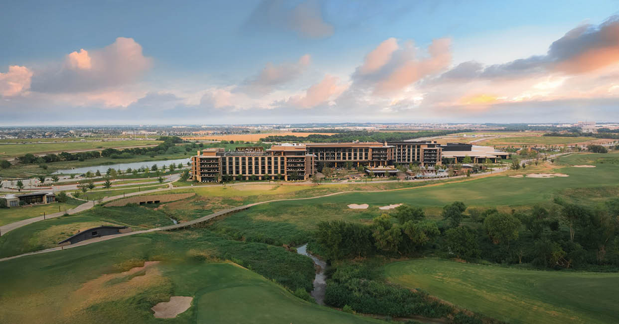 A large building is situated on a golf course with a green field and a river nearby. AI generated content