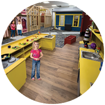 A young girl is standing in a play kitchen, surrounded by various toys and appliances. AI generated content