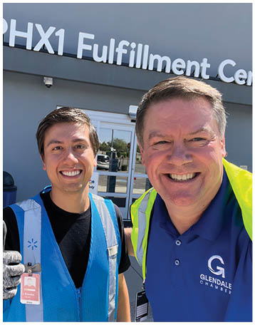 Two men are standing outside a building, one of them is wearing a blue vest and giving a thumbs up. AI generated content