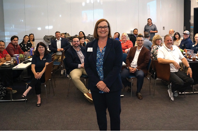 A woman in a blue shirt stands in front of a group of people. AI generated content