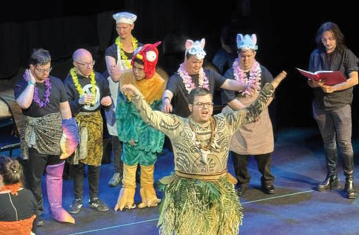A man in a grass skirt stands on stage with his arms outstretched, surrounded by other people. AI generated content