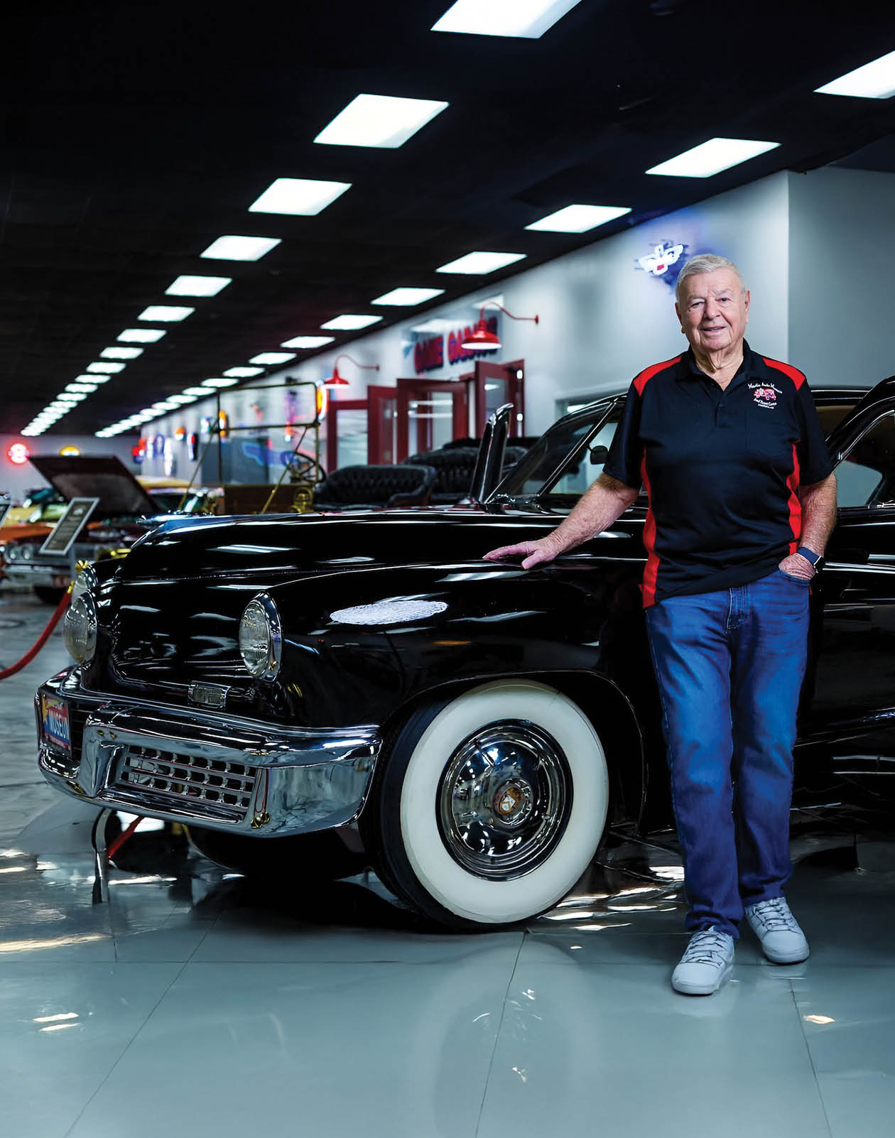 A man is standing next to a black car in a showroom. AI generated content