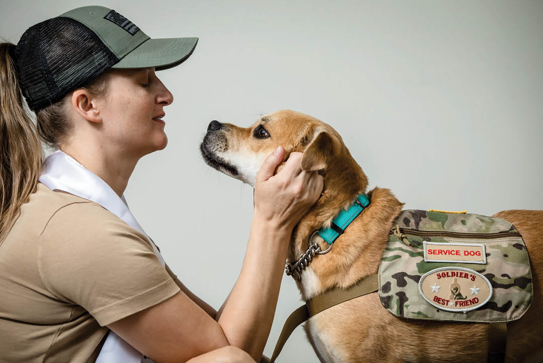 A woman is petting a dog with a camouflage vest on. AI generated content