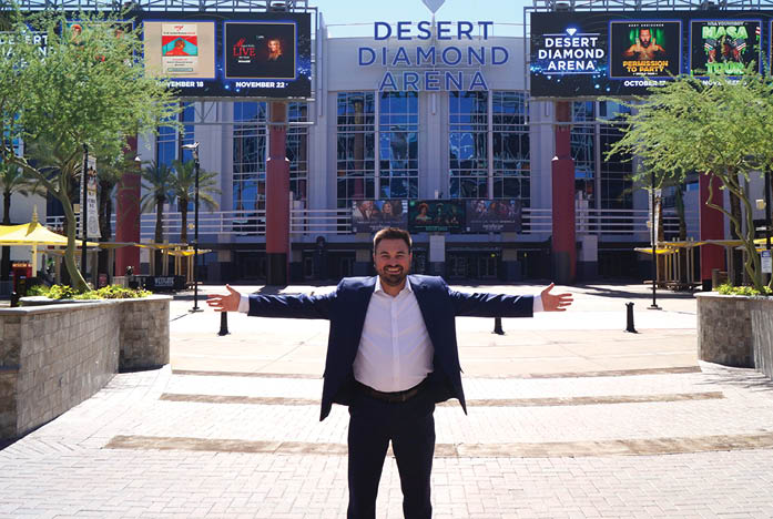 A man in a suit stands in front of a building with a large sign that says “Desert Diamond." AI generated content