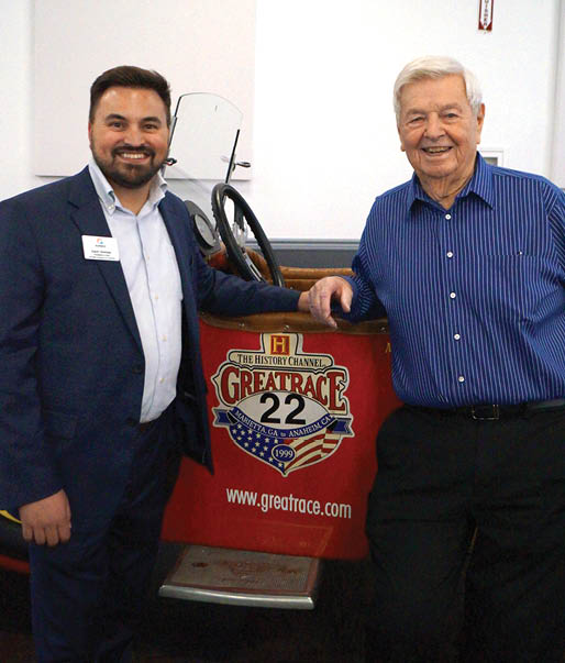 Two men are standing next to a red race car. AI generated content