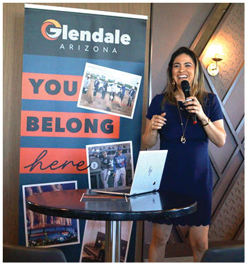 A woman is standing at a table with a laptop and a sign behind her. AI generated content