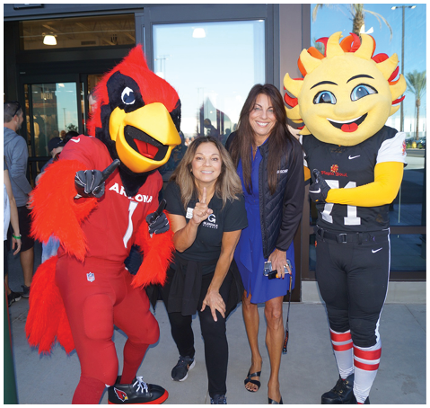 Two mascots in red and black costumes pose with a woman in a blue dress. AI generated content
