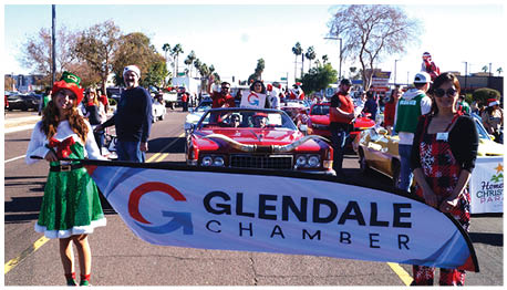A woman in a green dress holds a banner for the Glendale Chamber of Commerce. AI generated content