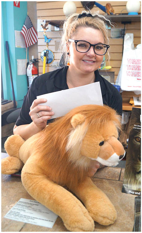 A woman is holding a piece of paper in front of a stuffed lion. AI generated content
