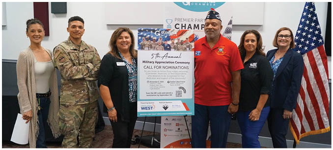 A group of people, including a man in a red shirt, pose in front of a banner. AI generated content