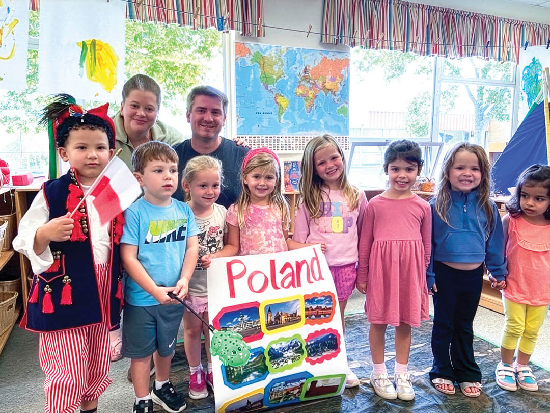 A group of children standing in front of a map of Poland. Description generated by AI