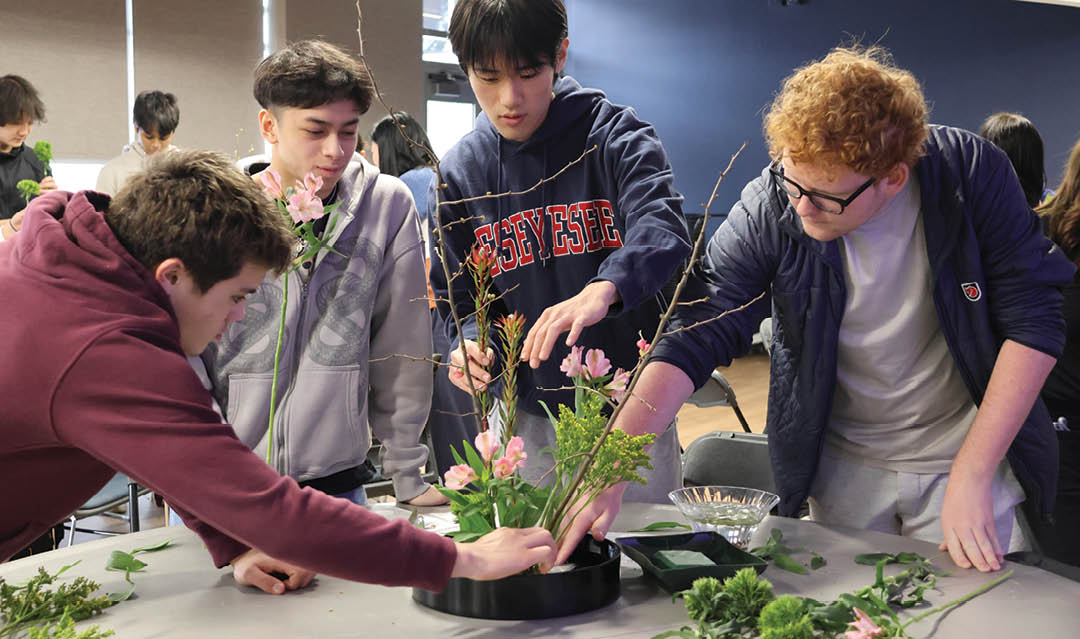 A group of people are looking at a plant in a pot. Description generated by AI