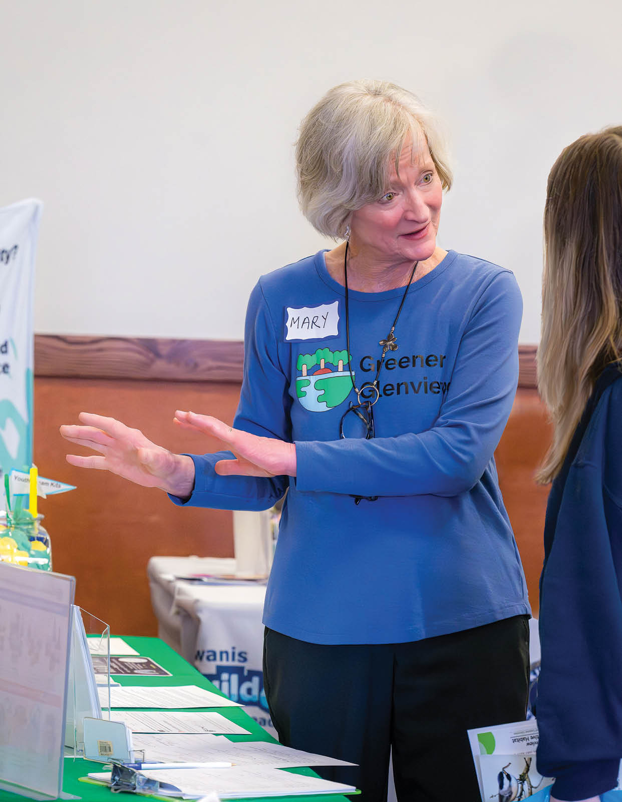 A woman wearing a blue shirt and a name tag. Description generated by AI