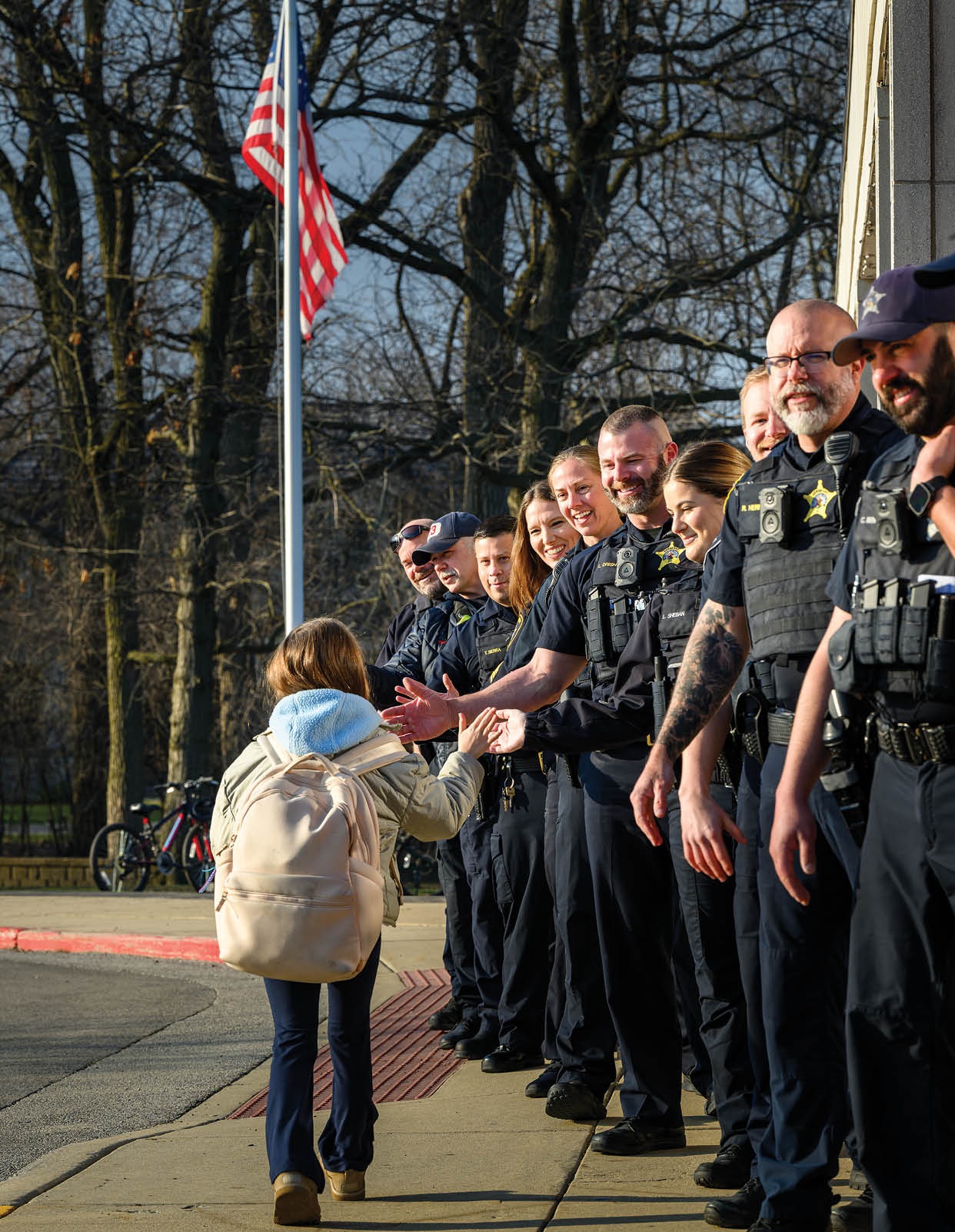 A group of police officers are lined up on a sidewalk. Description generated by AI