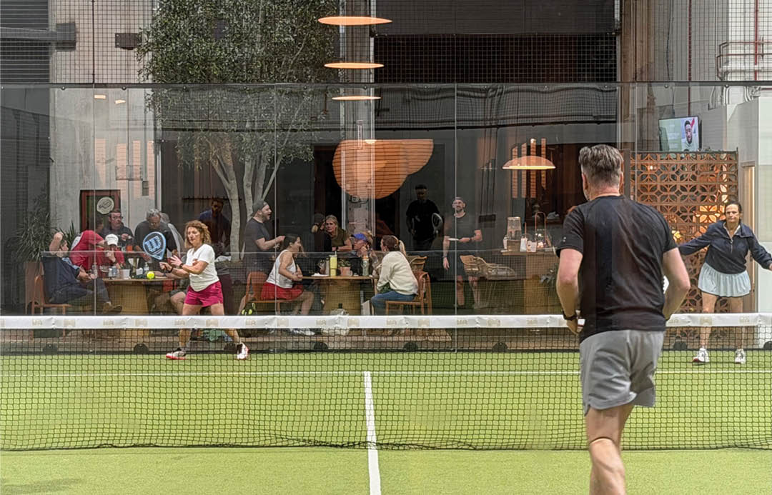 A tennis court with a net and a man playing tennis. Description generated by AI