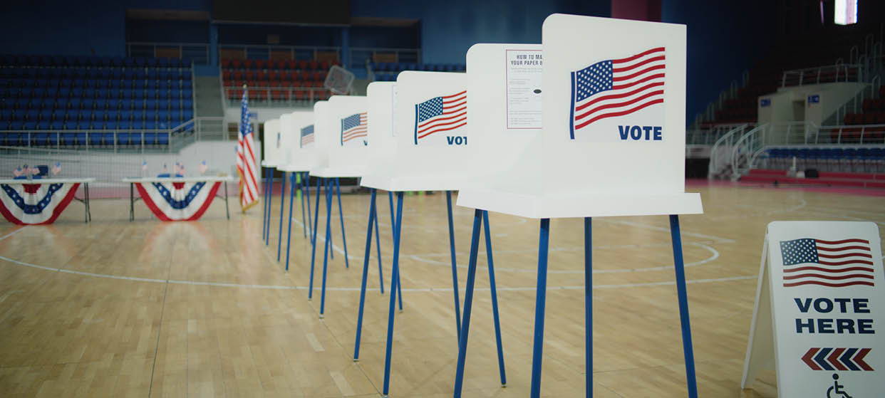 Voting booths with American flag logo at polling station. National Election Day in the United States of America. Presidential race and elections coverage. Civic duty, patriotism and democracy concept.