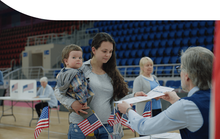 Female American citizen comes to vote in polling station. Woman with baby on hands talks with polling officer and takes bulletin. Political races of US presidential candidates. National Election Day.