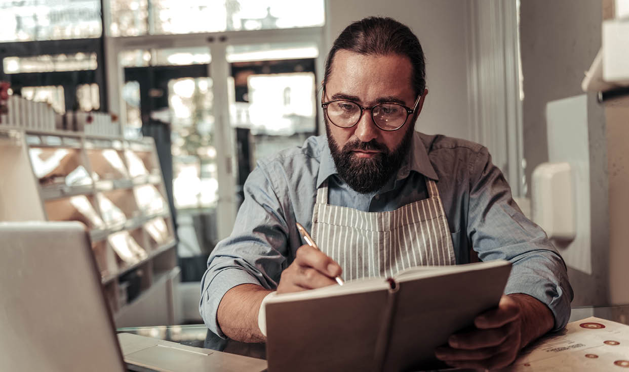 Small business. Smart serious man focusing on his work while checking a business plan