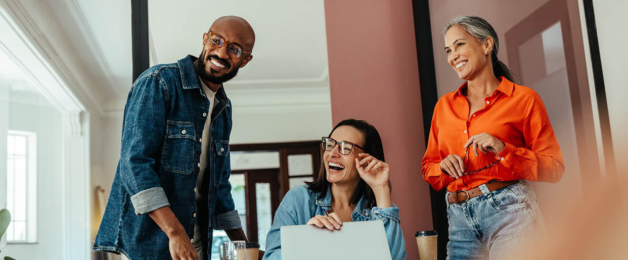 Group of creatives and freelancers enjoying collaboration in a modern, colorful office boardroom with a joyful team member.