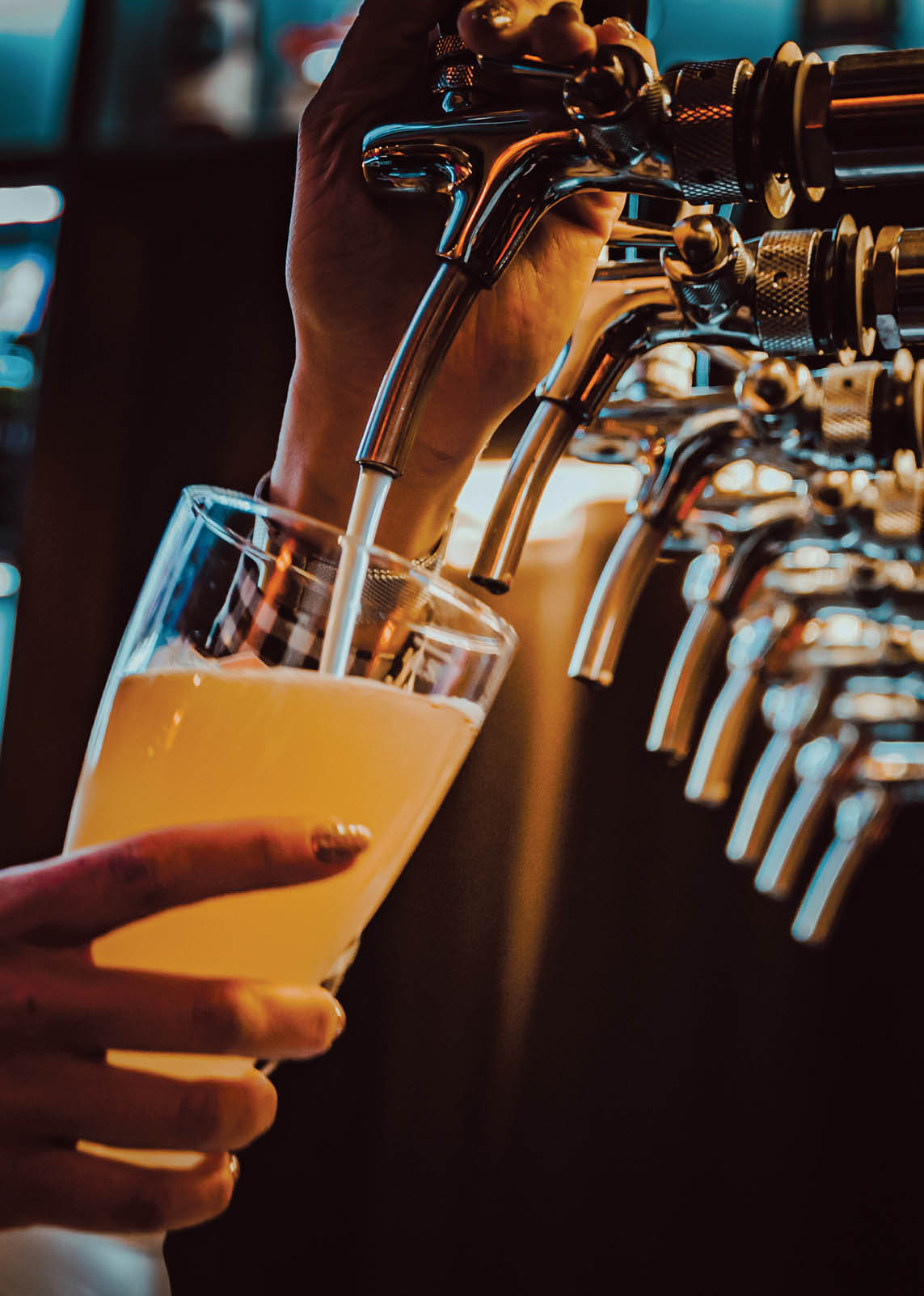 bartender hand at beer tap pouring a draught beer in glass serving in a restaurant or pub