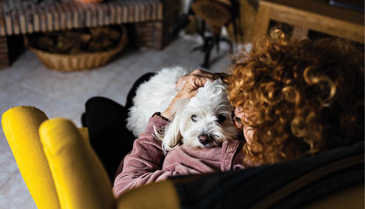 Senior woman wit her dog in front of the fireplace
