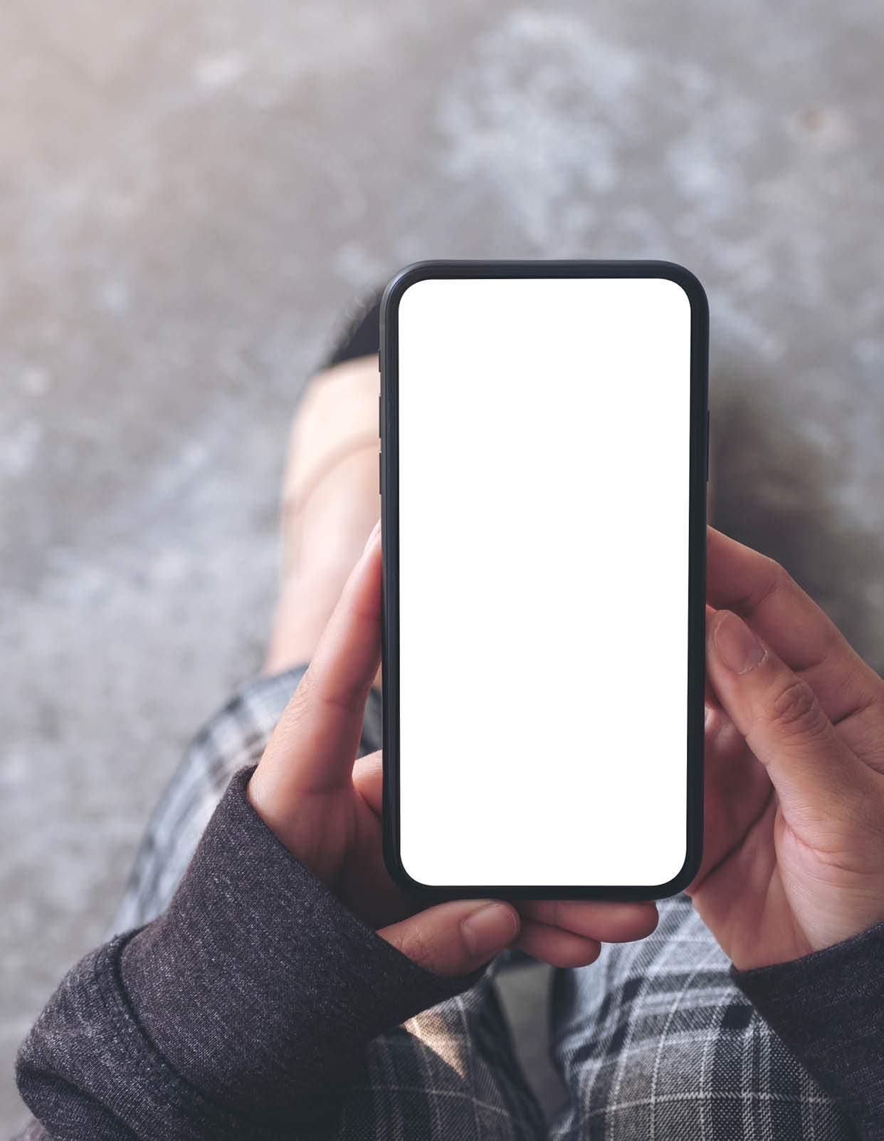 Top view mockup image of a woman holding black mobile phone with blank desktop screen while sitting on the floor