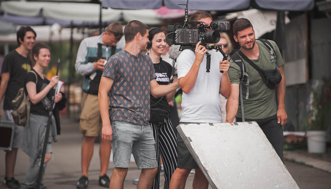Behind the scenes. Film crew team shooting movie scene on outdoor location. Group filmmaking set production