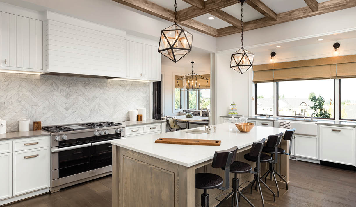 Kitchen Interior with Island, Sink, Cabinets, and Hardwood Floors in New Luxury Home. Includes elegant pendant light fixtures and wood beam ceiling