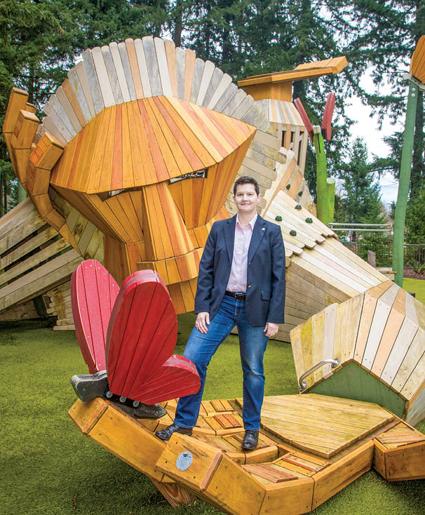 A man standing in front of a wooden sculpture of a lion. Description generated by AI