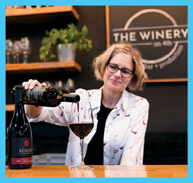 A woman pouring a glass of red wine. Description generated by AI