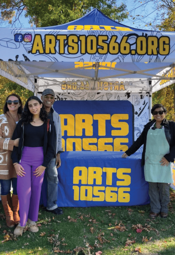 A group of people posing for a photo in front of a sign Description automatically generated