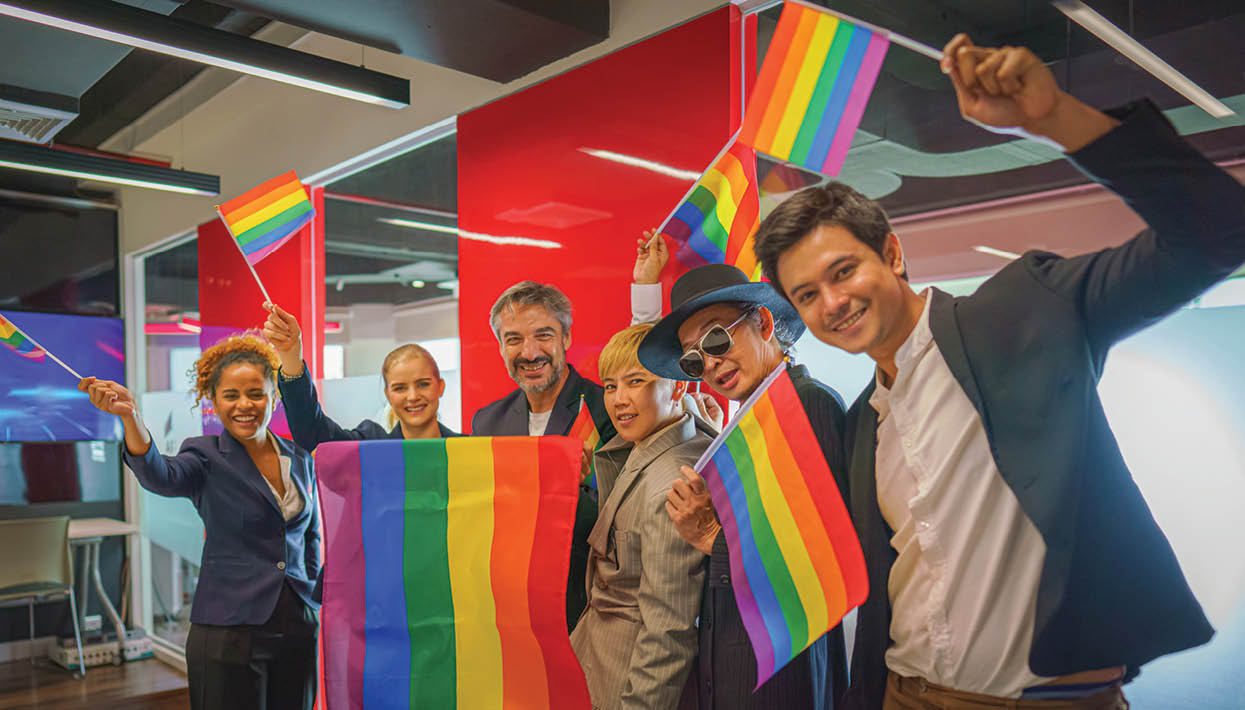 diverse group of business people (man, woman, gay, transgender, lesbian, asian, caucasian, african american, lgbtq) with rainbow flag on hand combine together as teamwork in office, selective focused