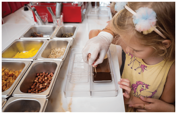 Baby girl in the workshop during a lesson on making handmade chocolates and sweets.