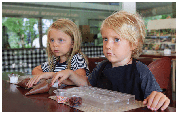 Blond girl and little boy at a chocolate workshop in Bali. A hands-on, educational activity for children traveling with family.
