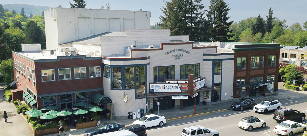 A busy street with cars and trucks driving by a theater. AI generated content