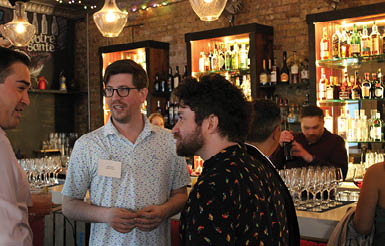 A group of people standing around a bar. Description generated by AI