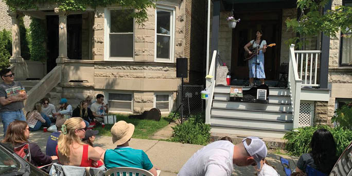 A woman is playing guitar on a stage in front of a crowd of people. Description generated by AI